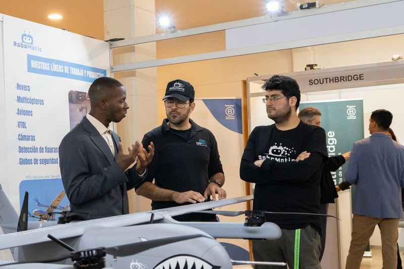 Visitantes conversan con un expositor frente a un ala fija VTOL